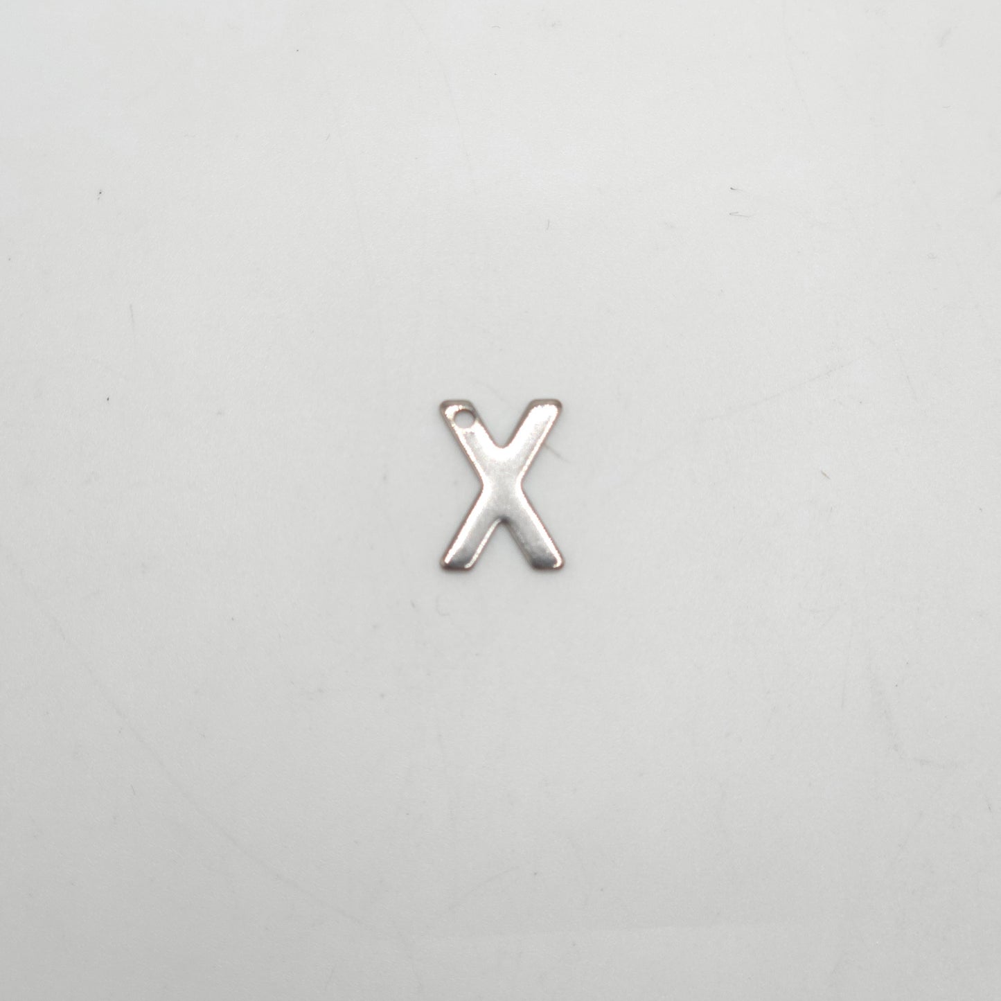 Silver 'X' charm on a light gray background