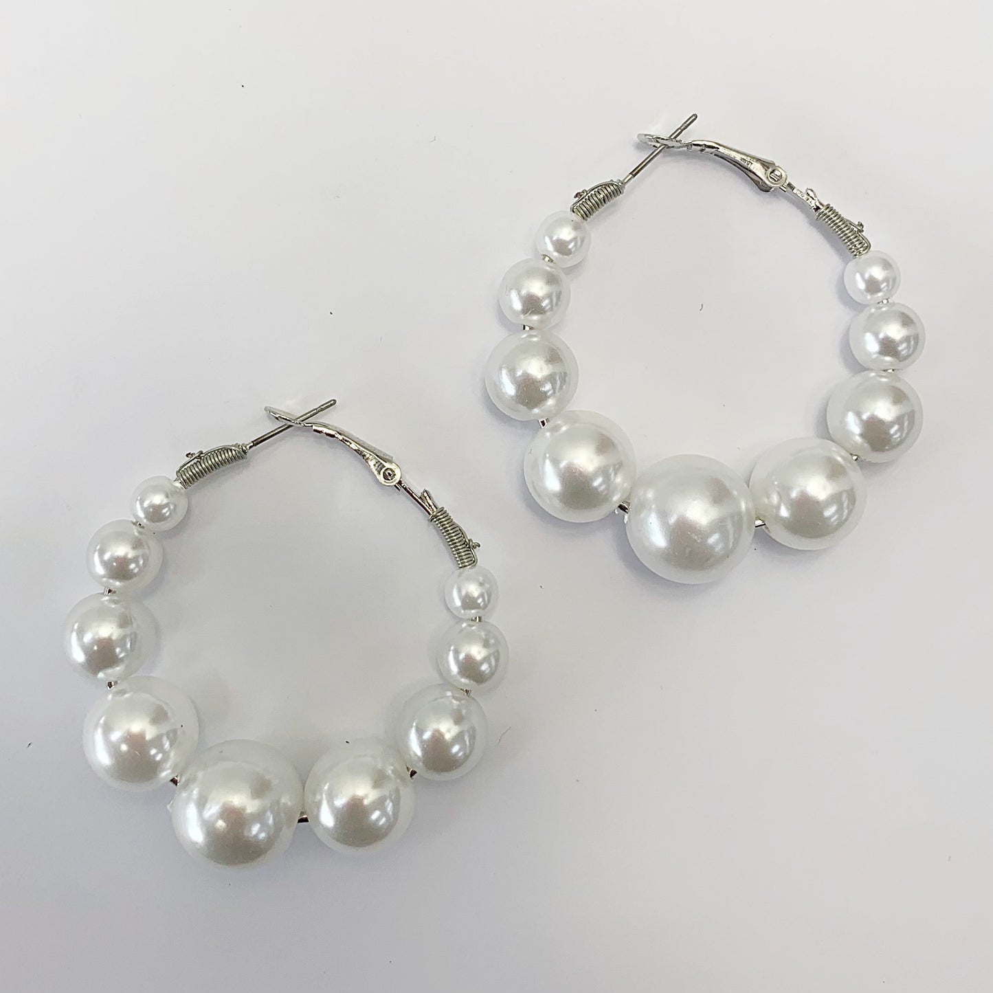 Oversized hoop earrings with graduated faux pearl accents in a glamorous boutique fashion style.