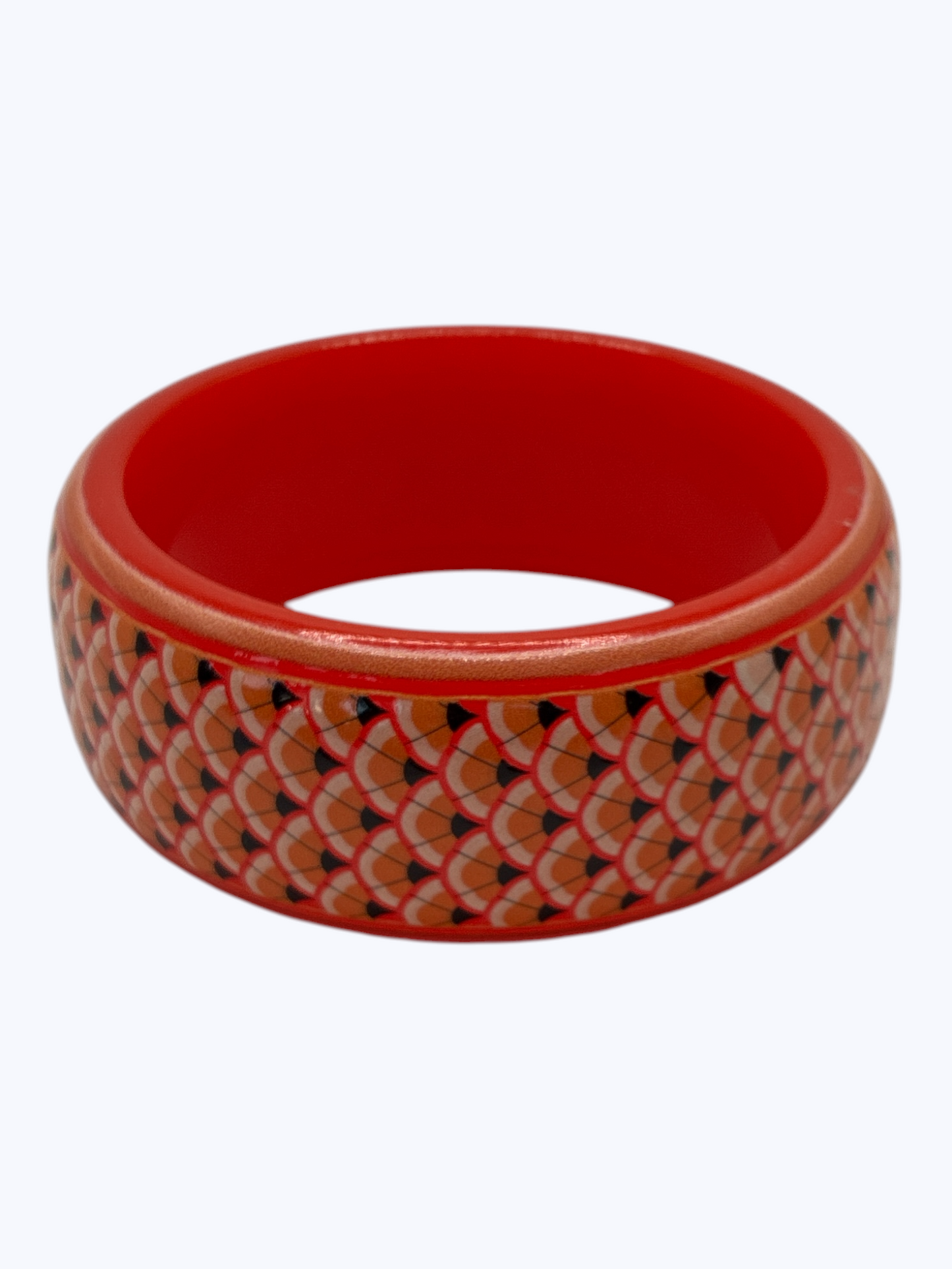 Red bangle with a patterned design on a white background