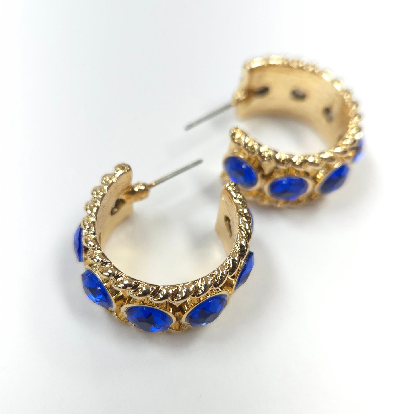 Gold hoop earrings with blue gemstones on a white background