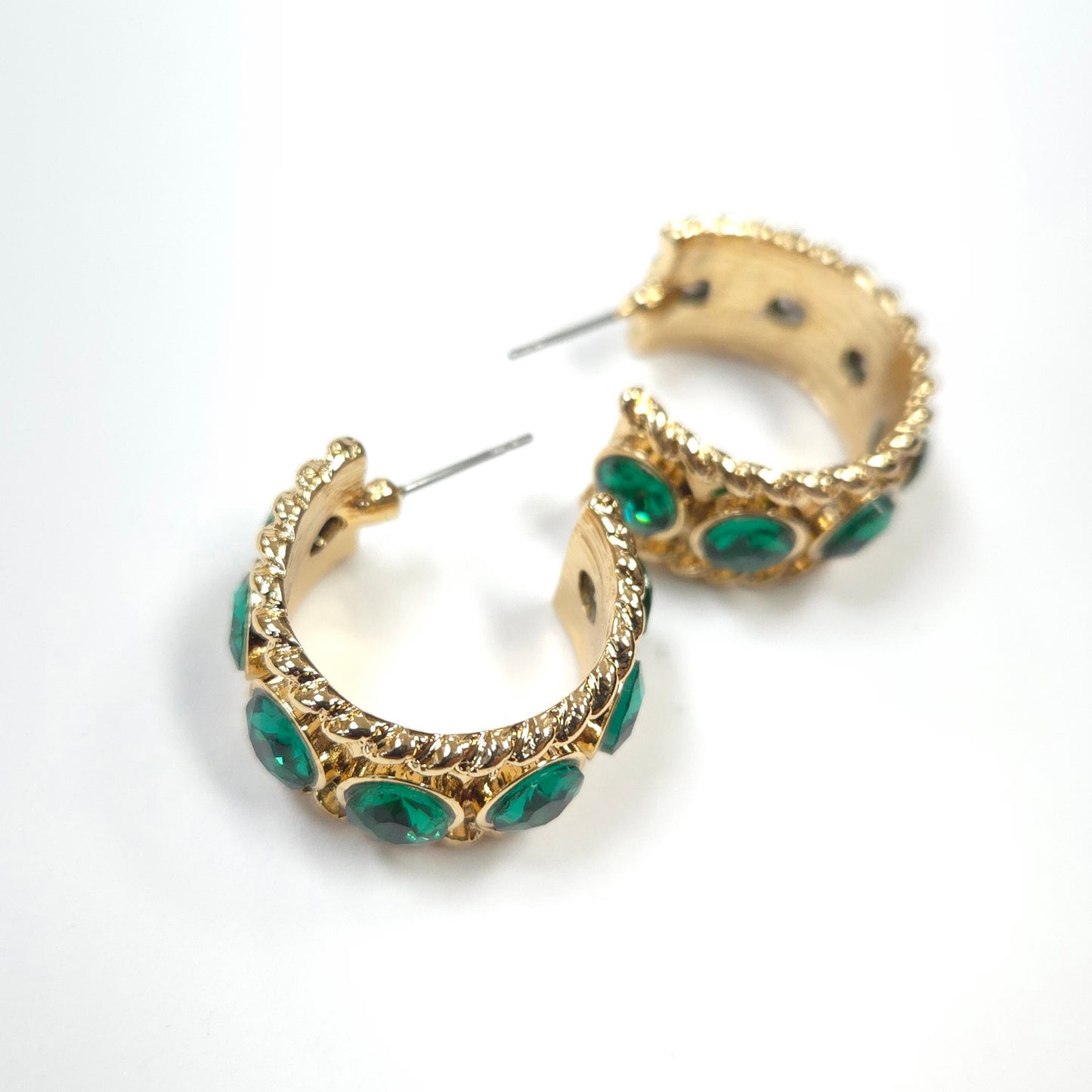 Gold hoop earrings with green gemstones on a white background