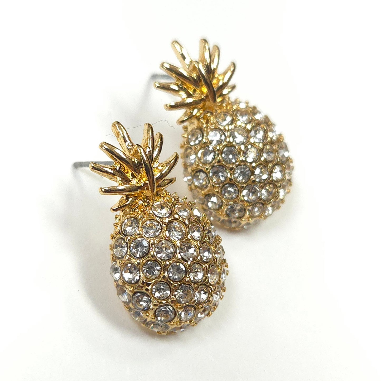 Gold pineapple earrings with crystal details on a white background