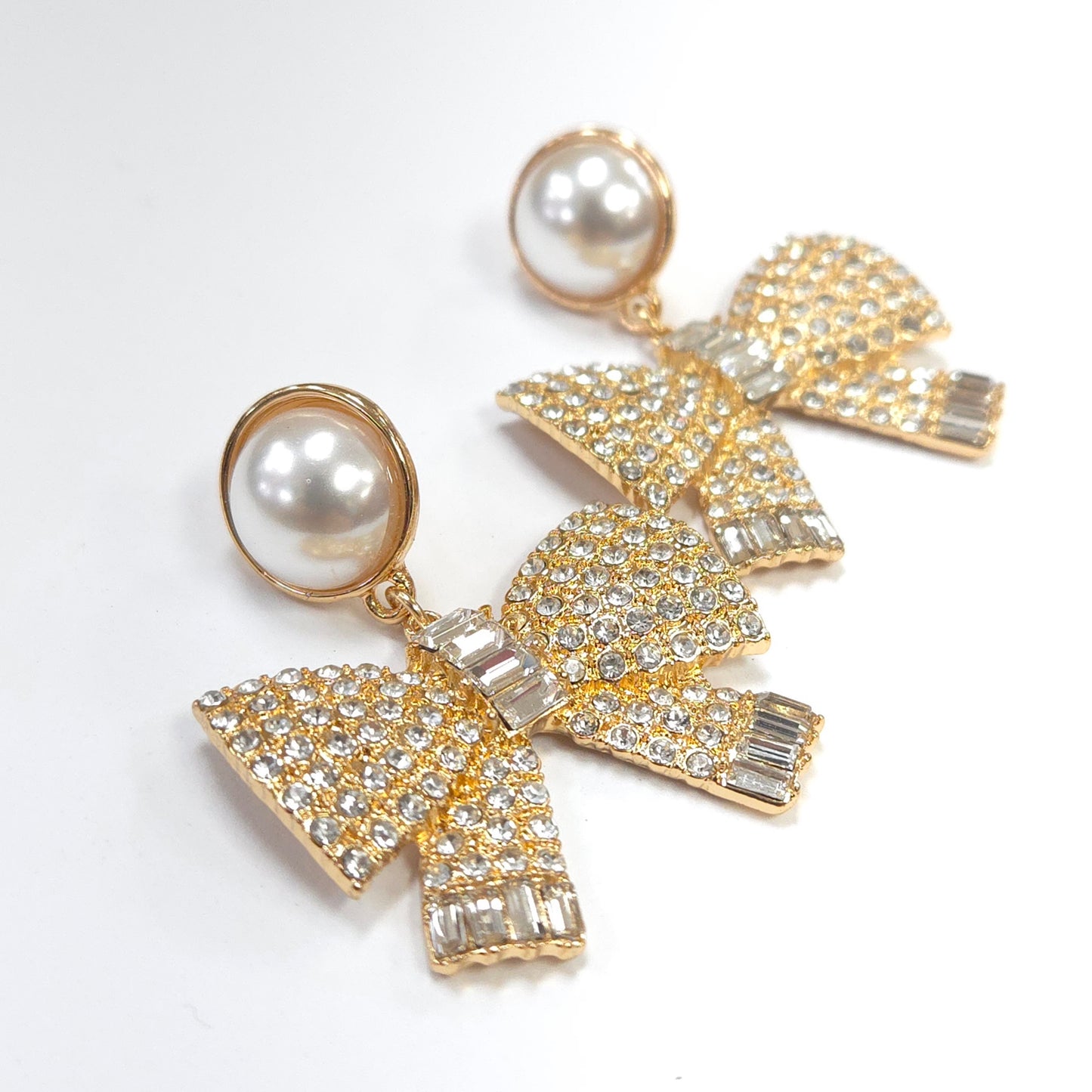 Bow-shaped earrings with pearl centers on a white background