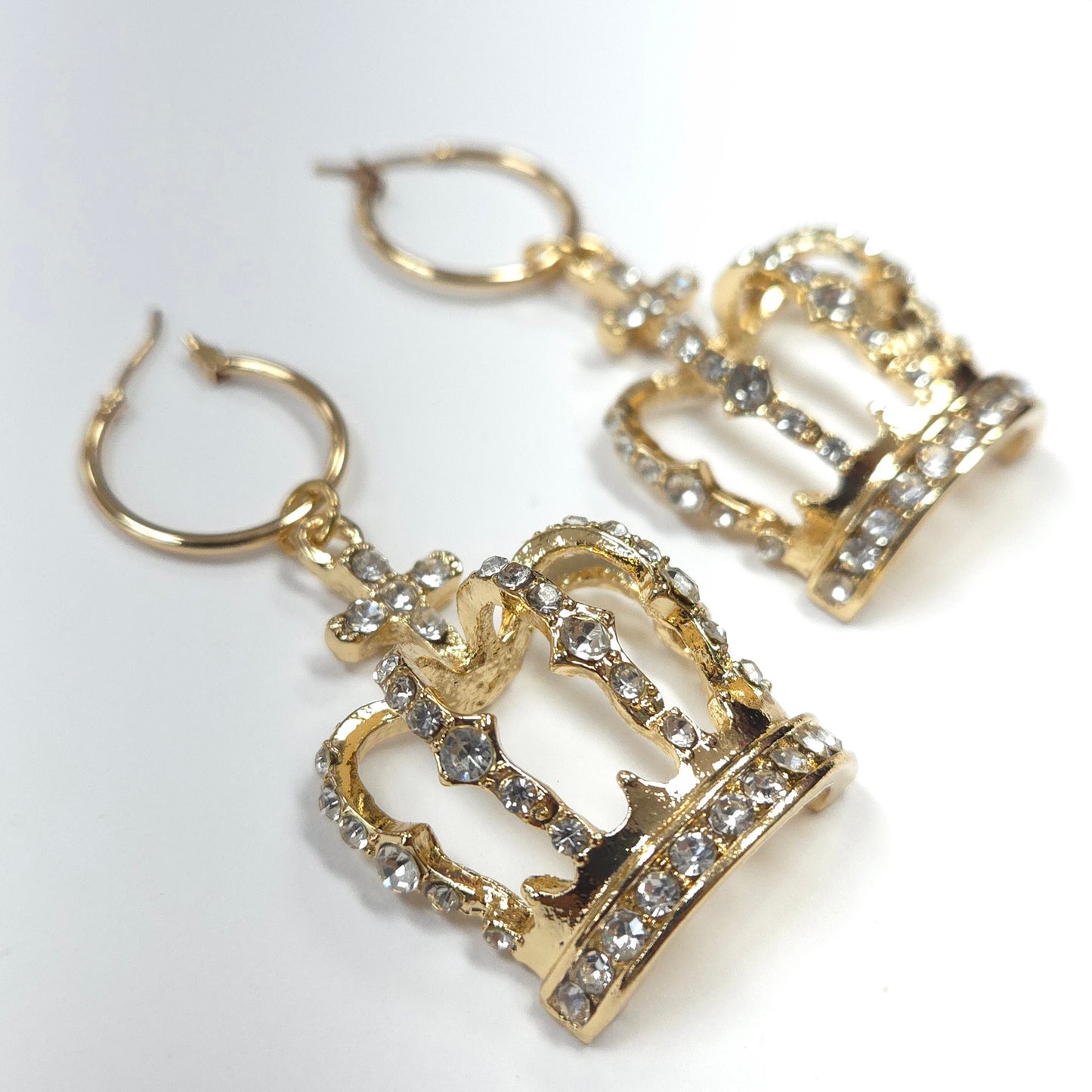 Gold crown-shaped earrings with rhinestones on a white background