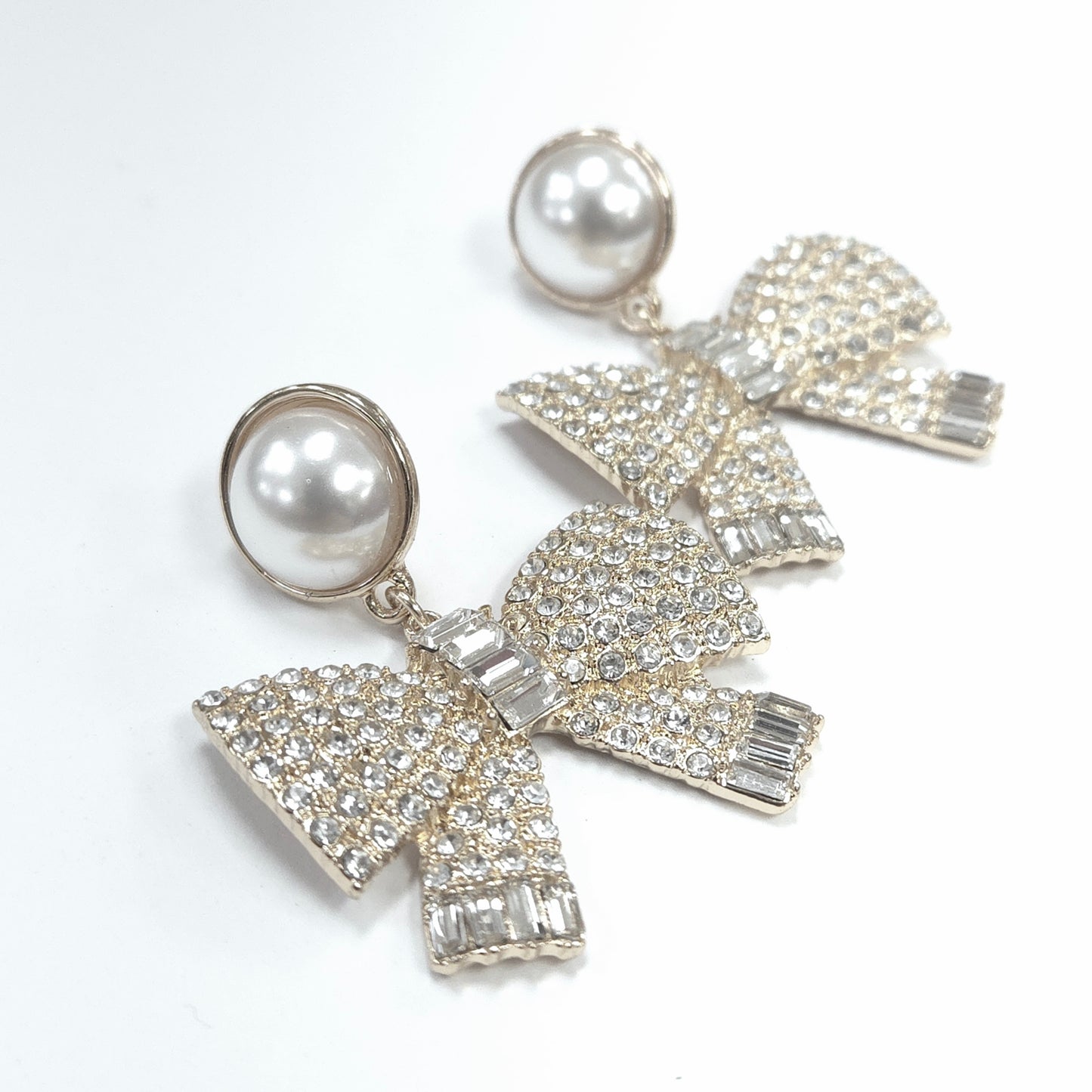 Bow-shaped earrings with pearl centers on a white background
