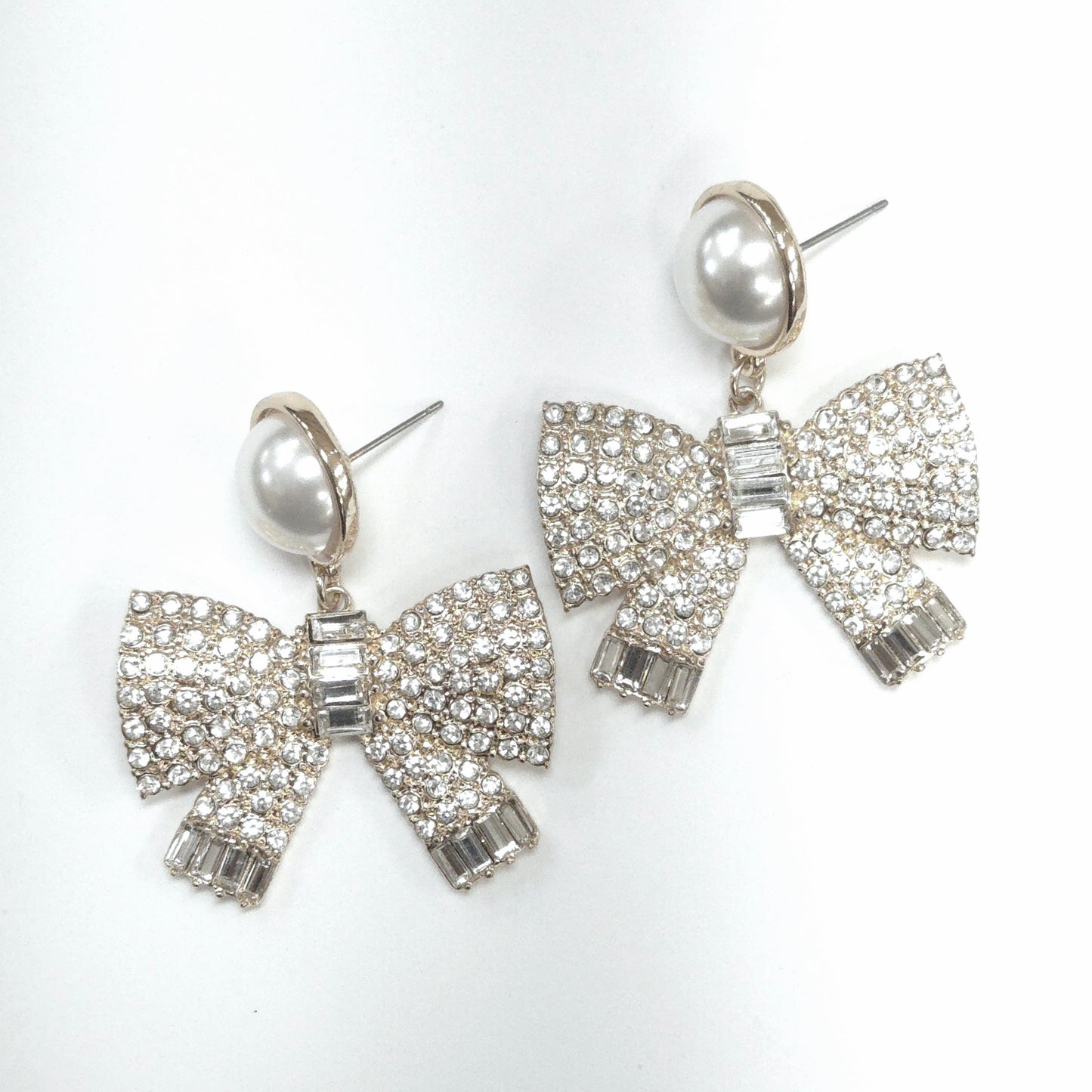 Bow-shaped earrings with pearl centers on a white background