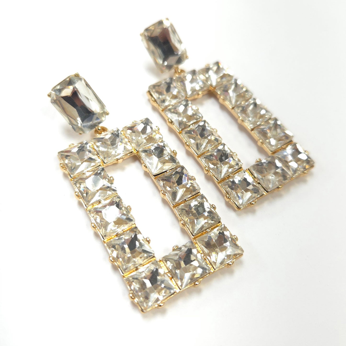 Pair of gold-framed crystal earrings on a white background