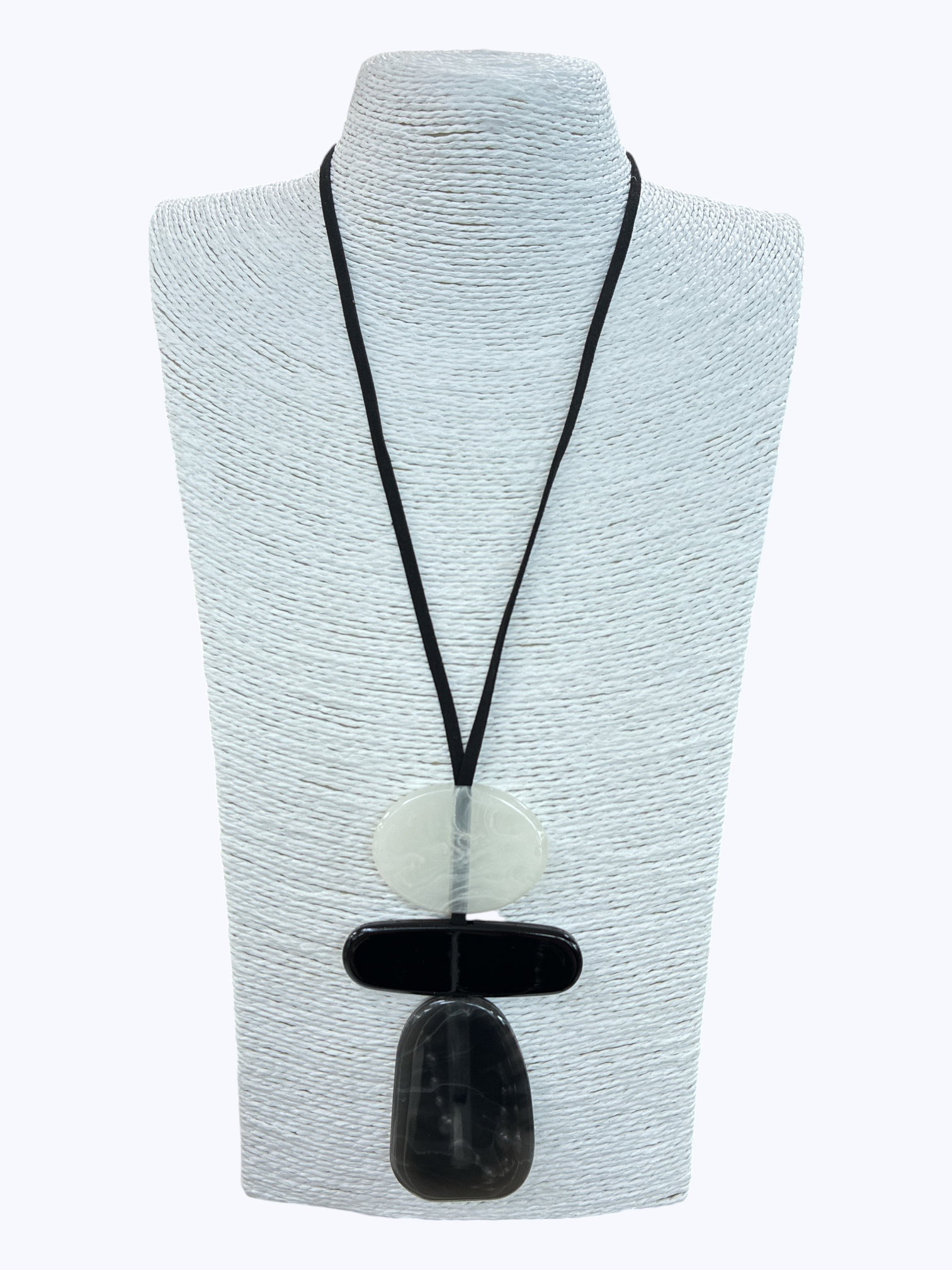 Black and white geometric pendant necklace with layered abstract resin shapes and minimalist cord design on mannequin display