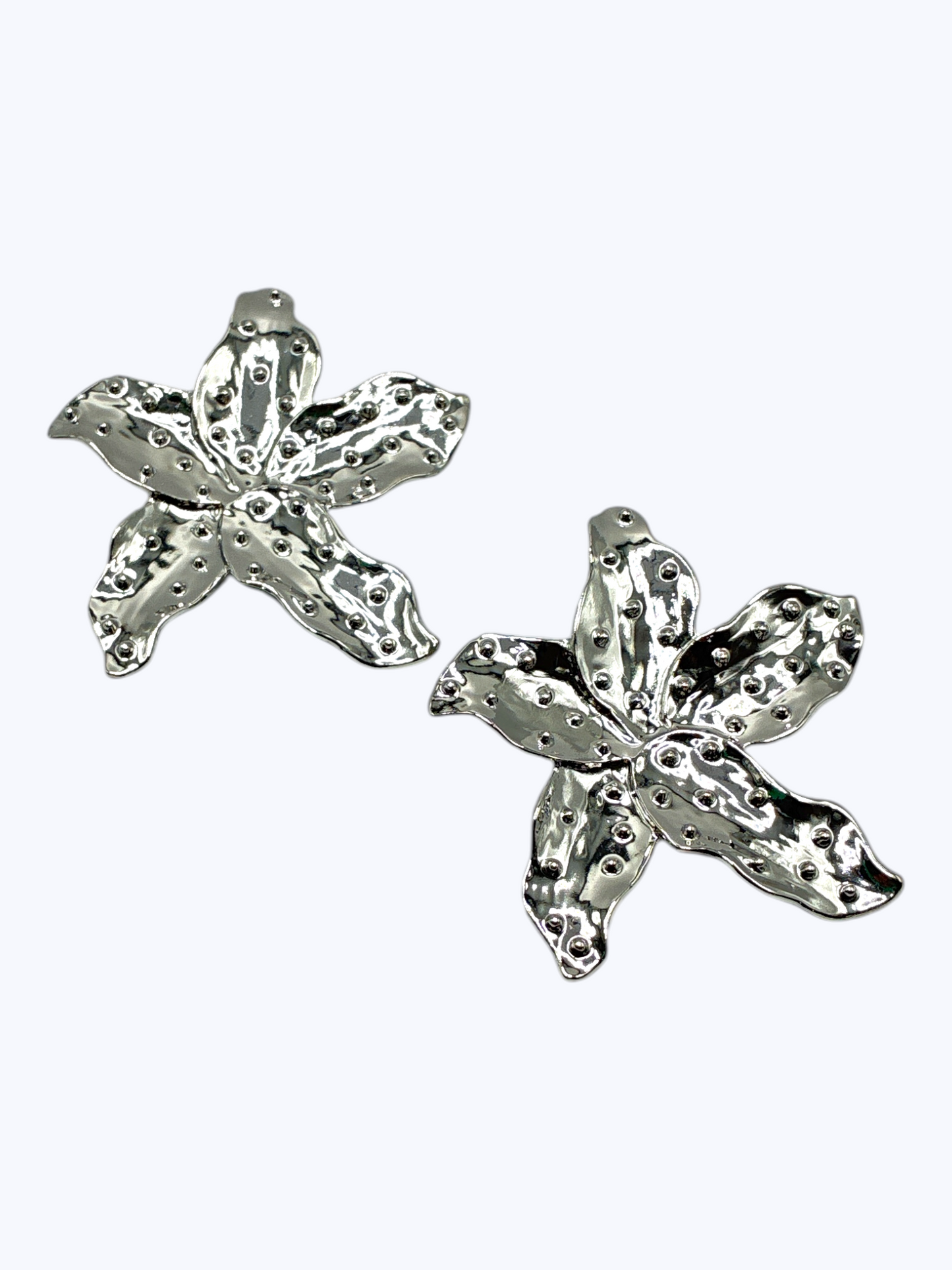 Silver floral statement earrings with textured metallic petals and sculpted detailing for a bold contemporary boutique look.