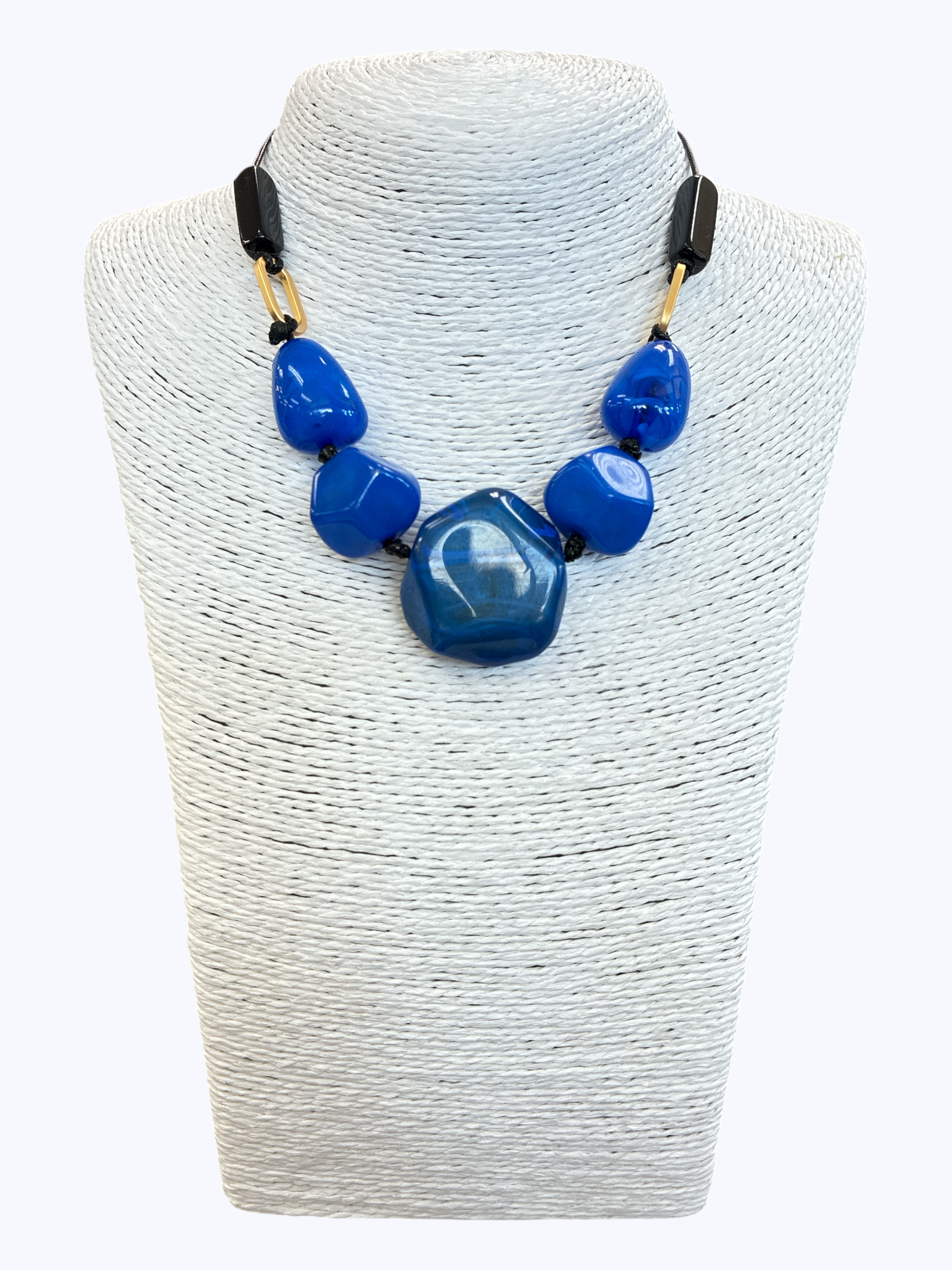 Blue statement bead necklace with glossy marbled resin stones, black cord, and gold-tone accents for a bold contemporary boutique look.