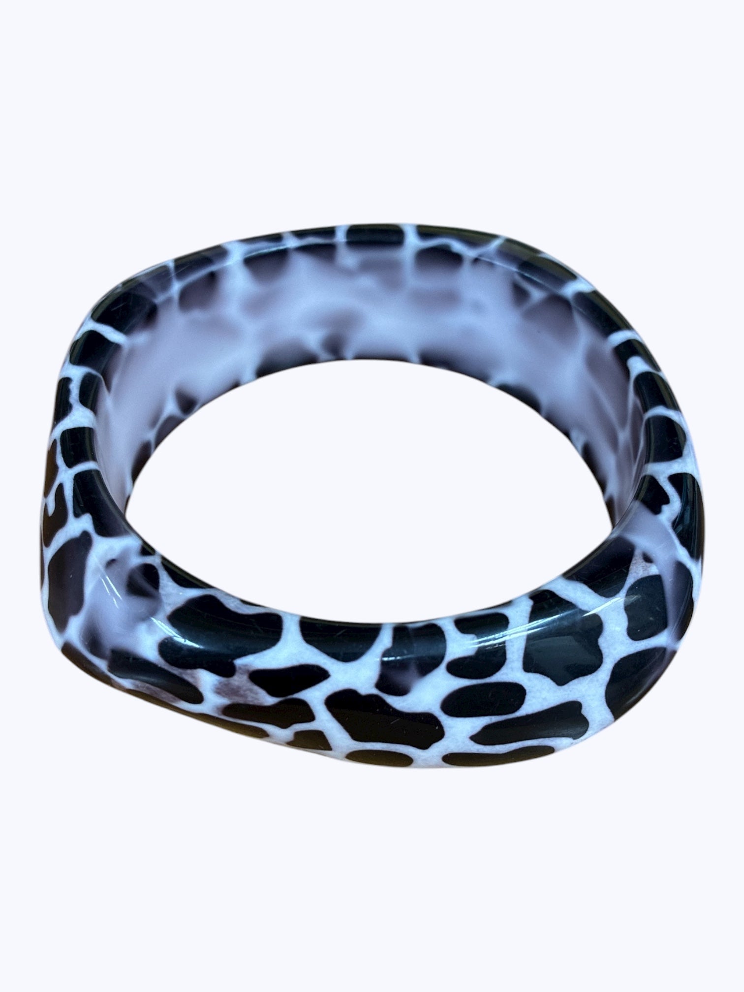 Chunky resin bangle bracelet featuring an abstract speckled animal-inspired pattern with a glossy sculpted finish.