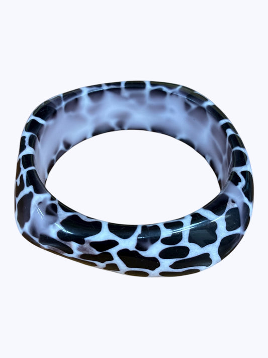Chunky resin bangle bracelet featuring an abstract speckled animal-inspired pattern with a glossy sculpted finish.