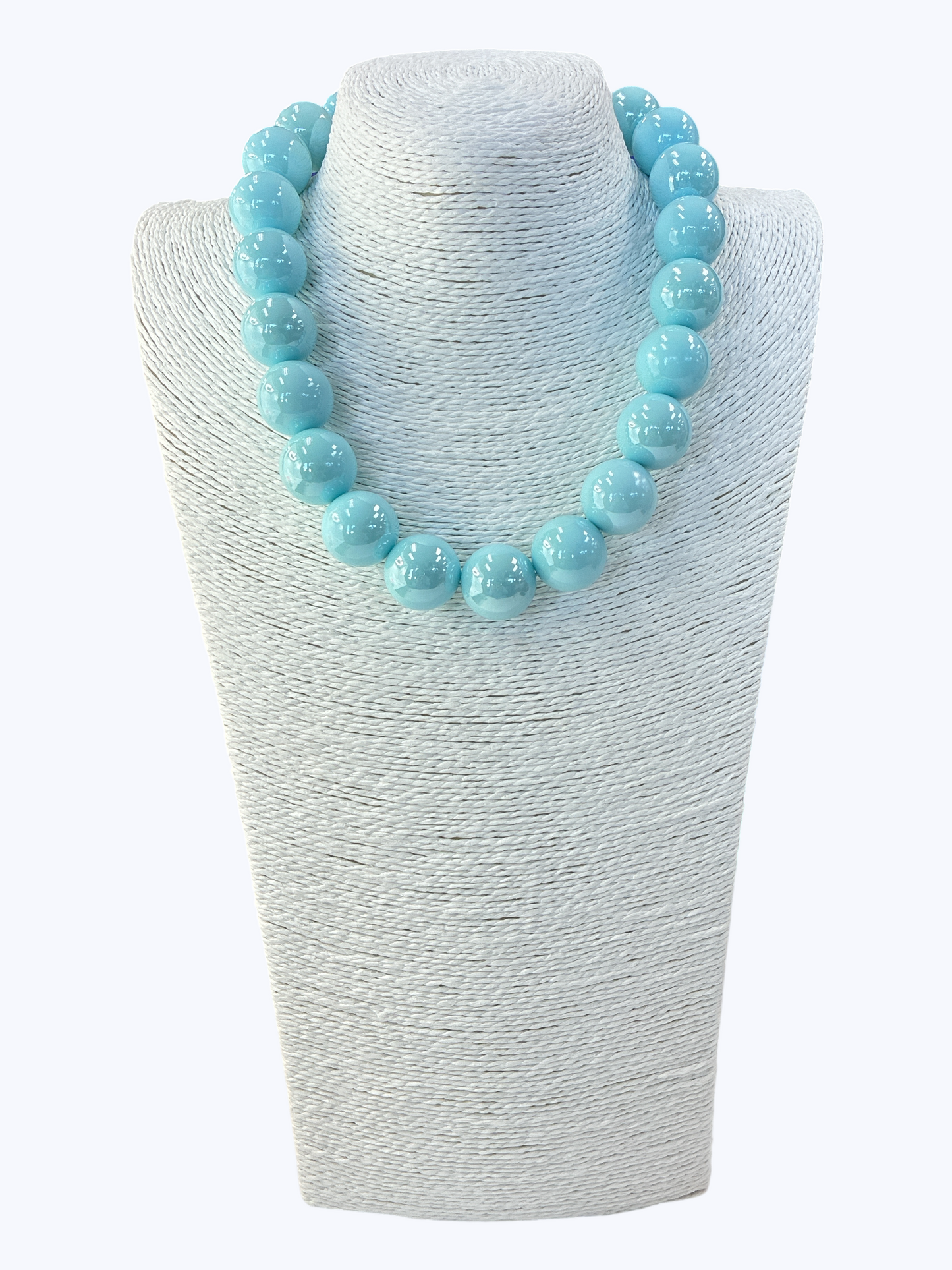 Turquoise beaded necklace on a textured white stand
