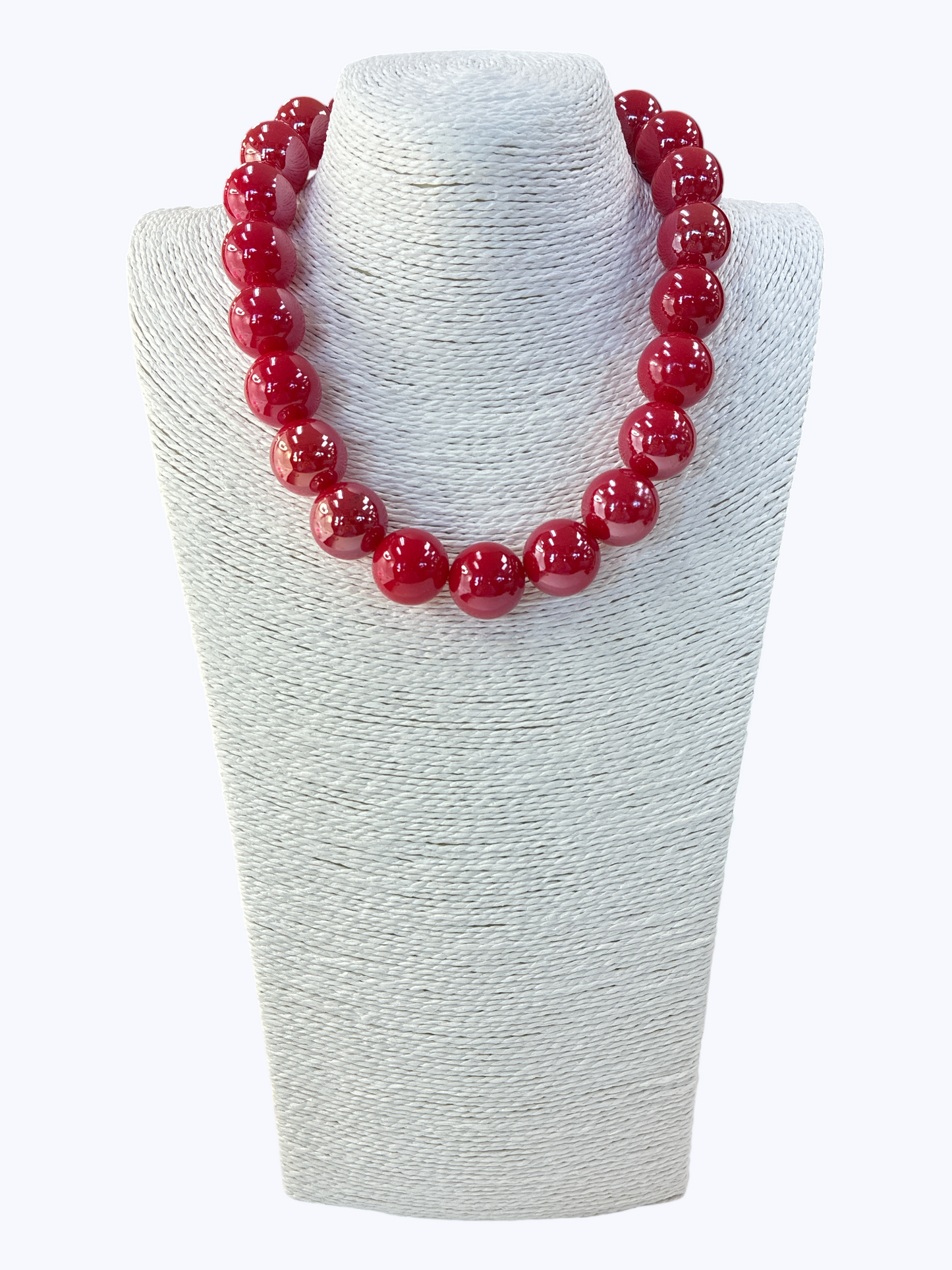 Fuchsia beaded necklace on a white textured stand