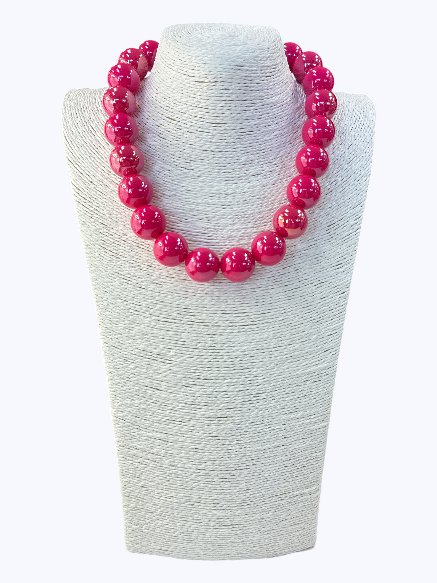 Pink beaded necklace on a white textured stand