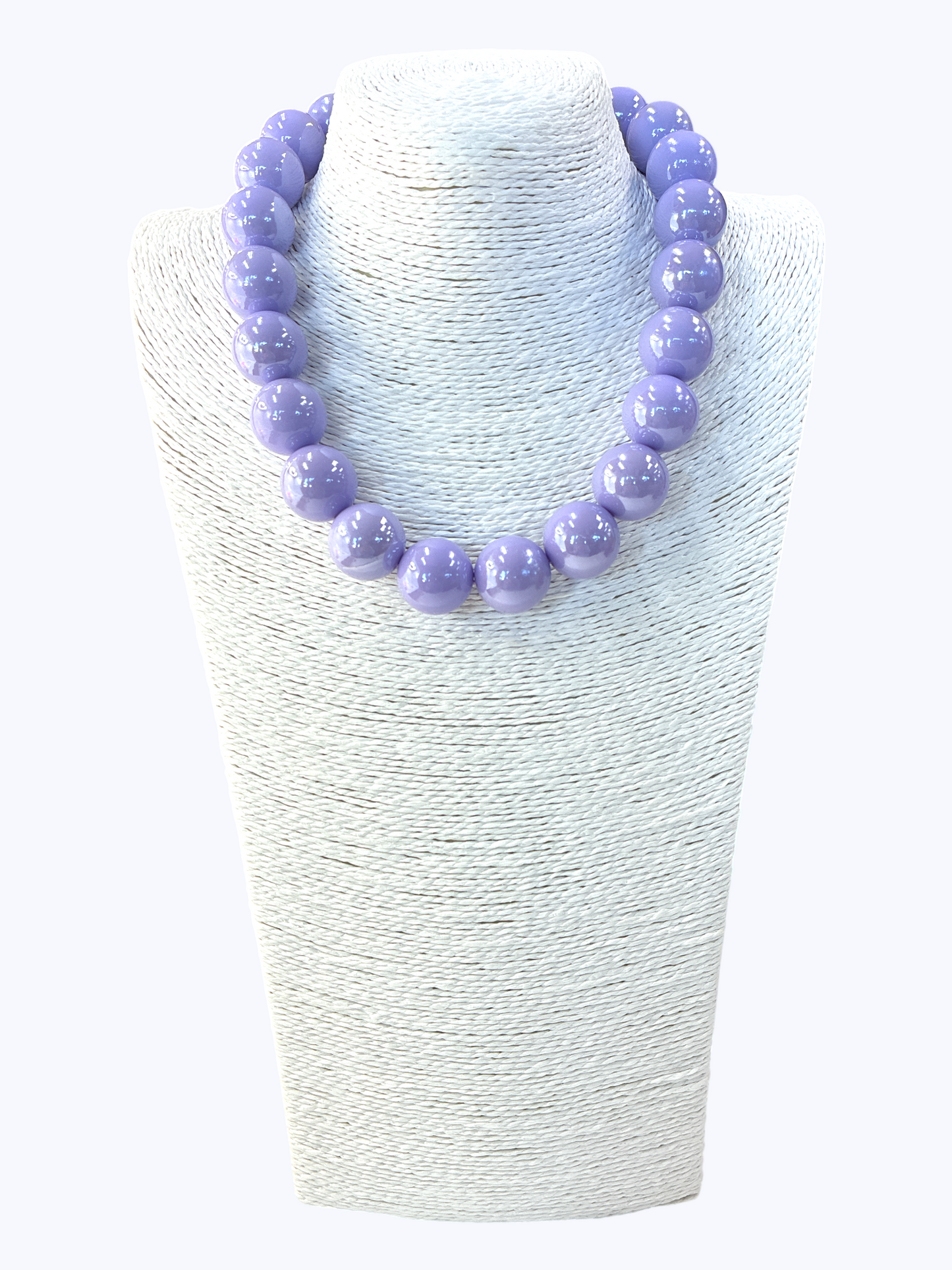Purple beaded necklace on a white textured stand