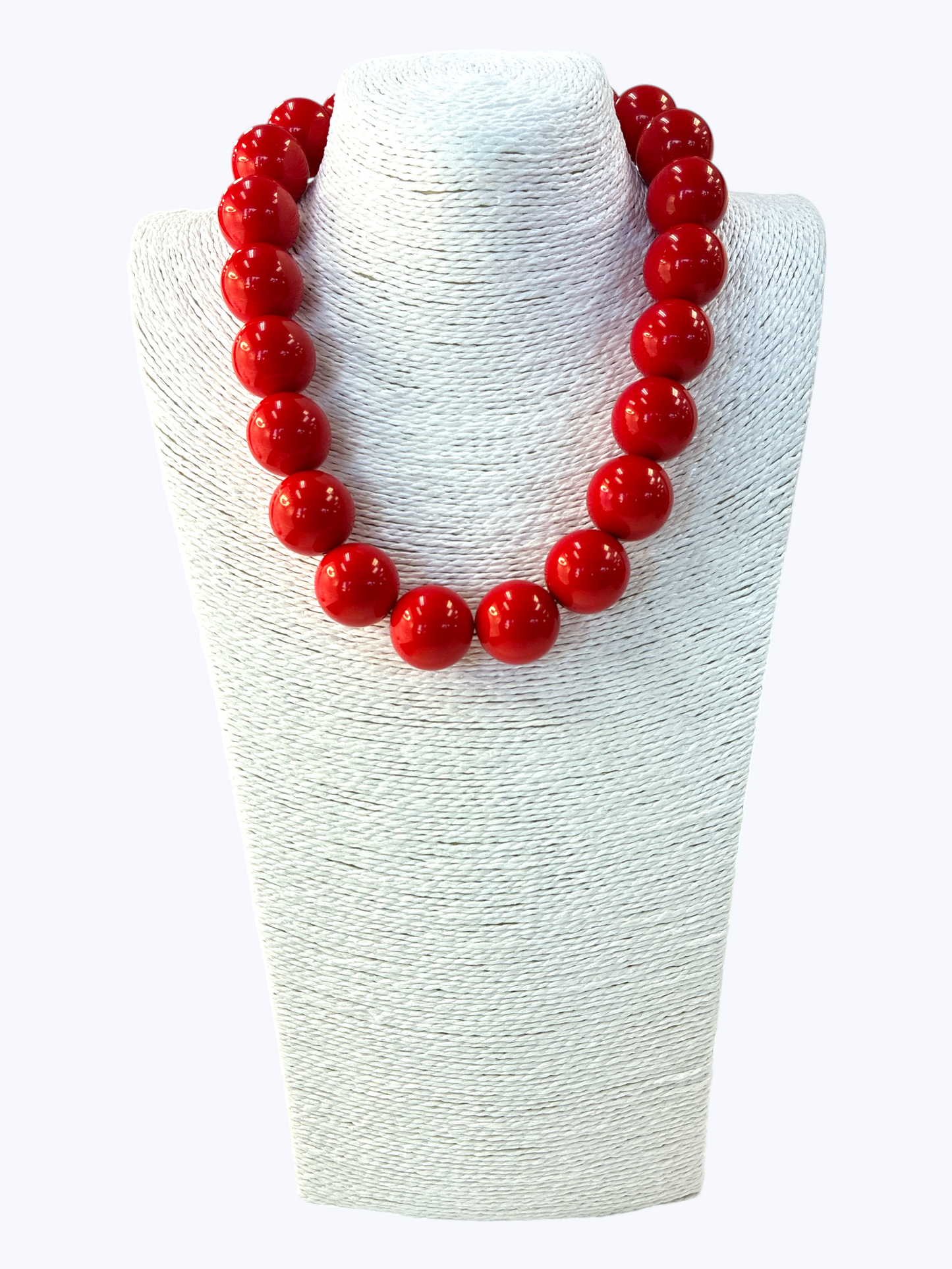 Red beaded necklace on a white textured stand
