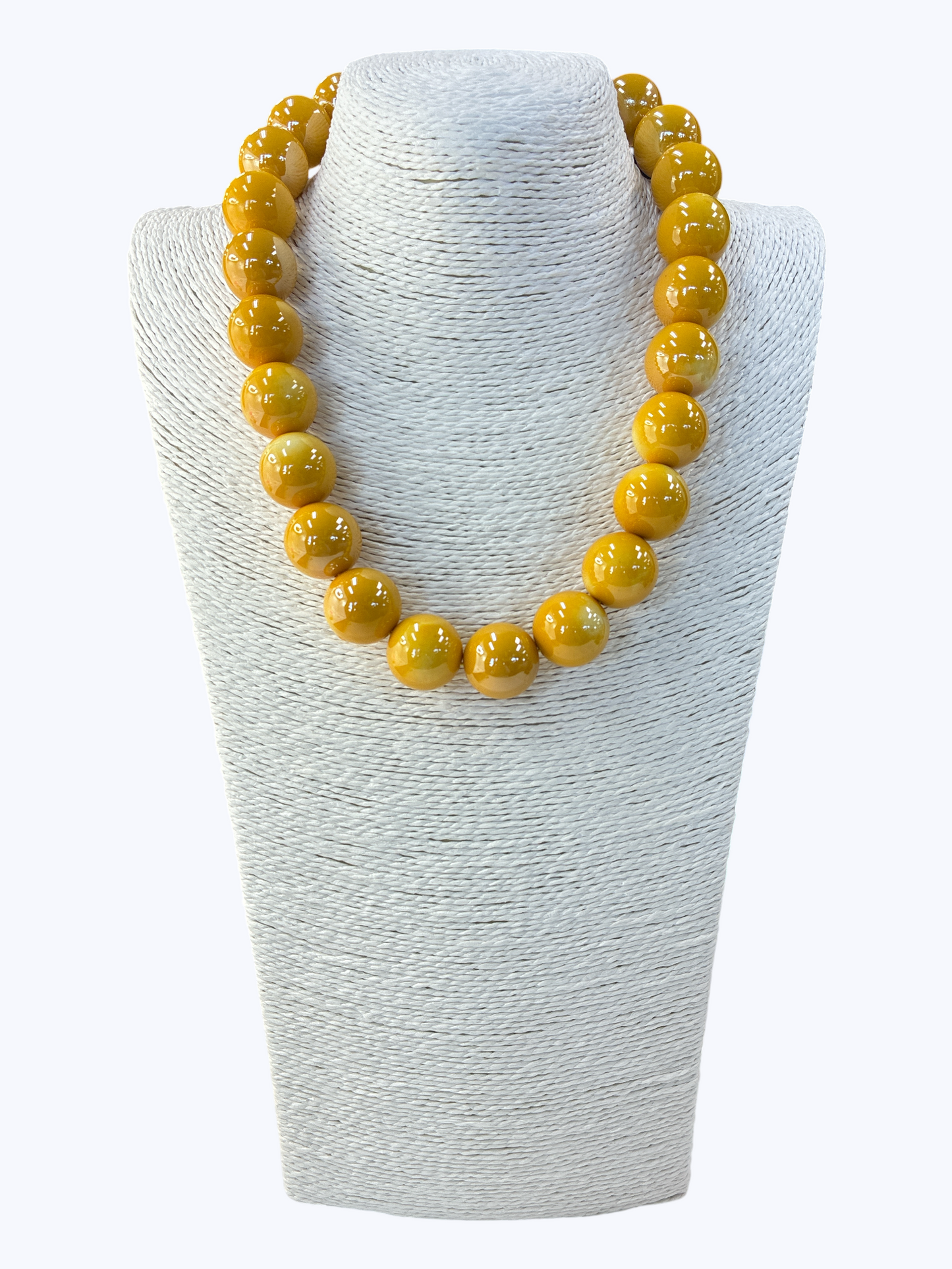 Yellow beaded necklace on a white textured stand