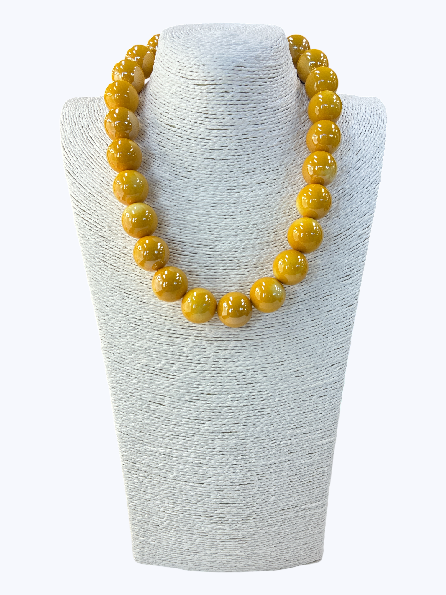 Yellow beaded necklace on a white textured stand