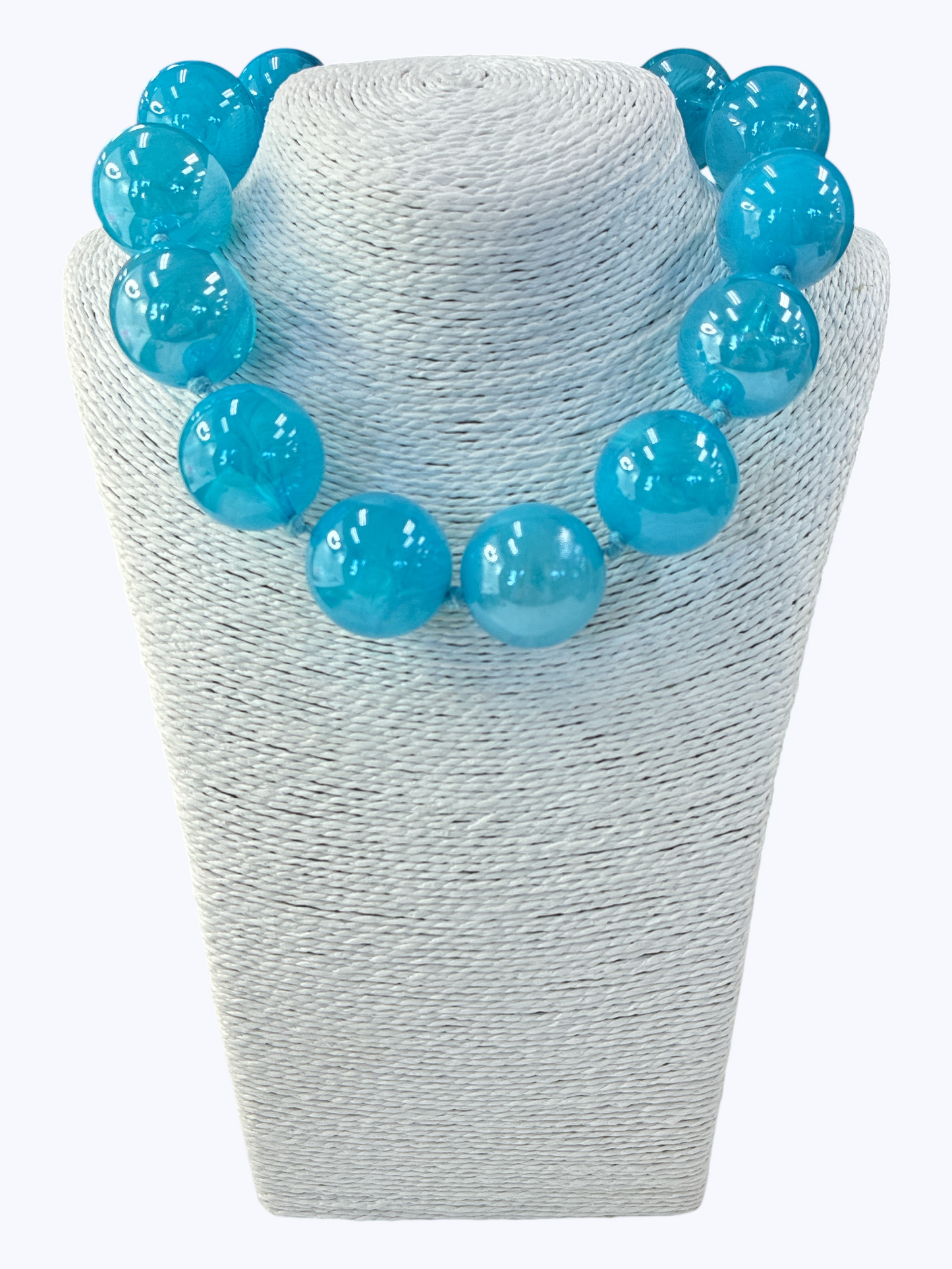Turquoise beaded necklace on a white textured stand
