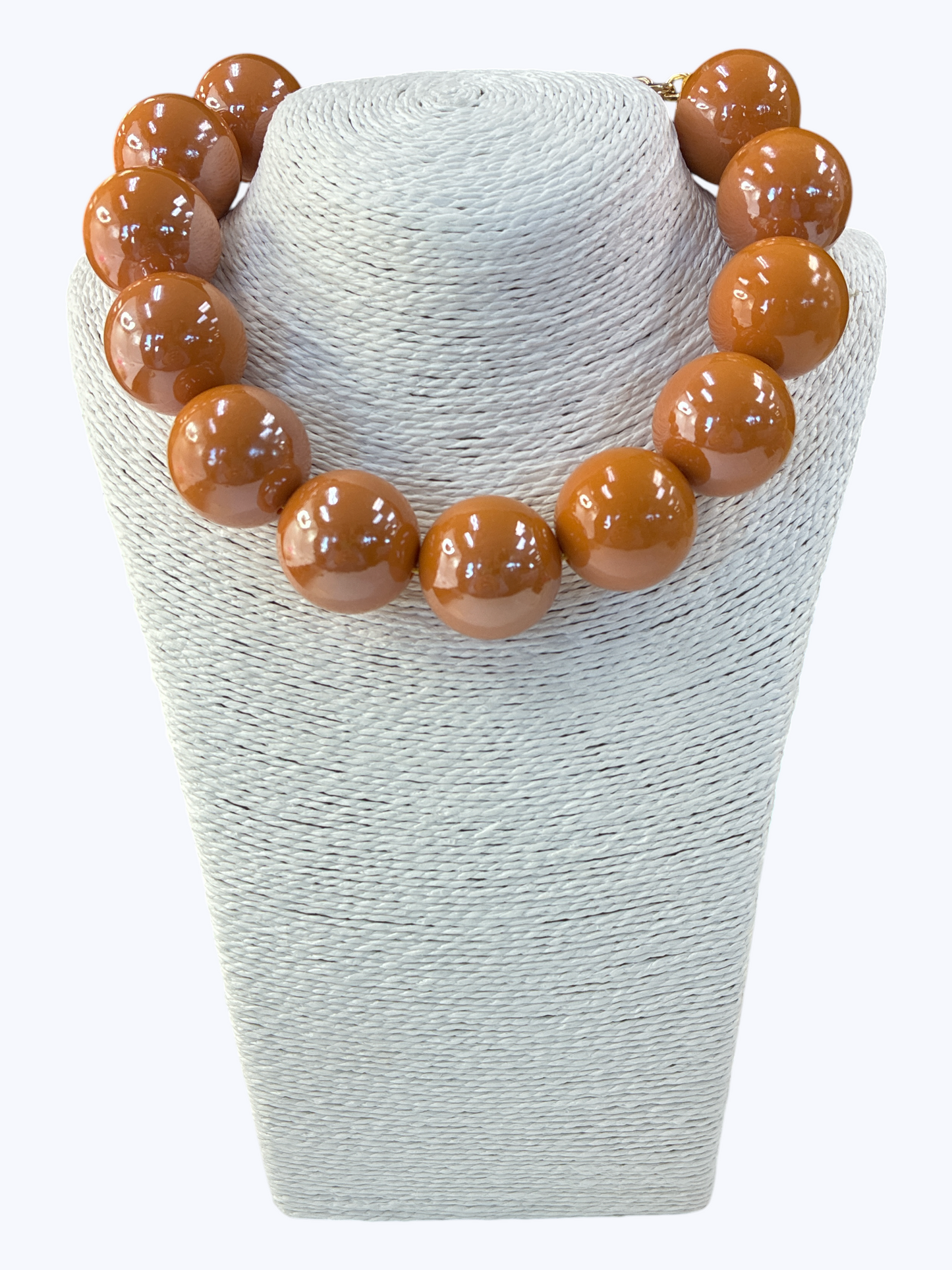 Necklace with brown beads on a textured white stand