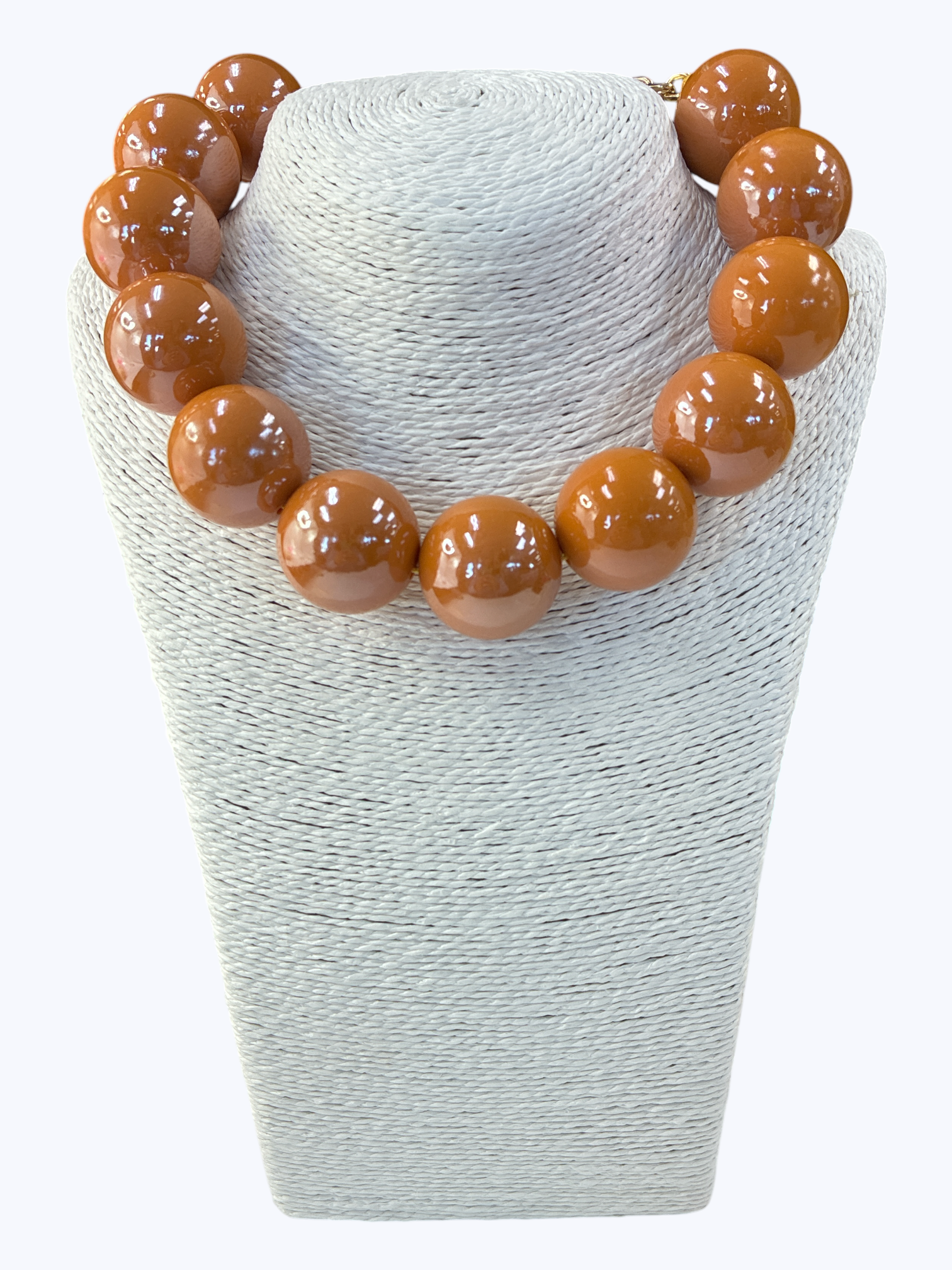 Necklace with brown beads on a textured white stand