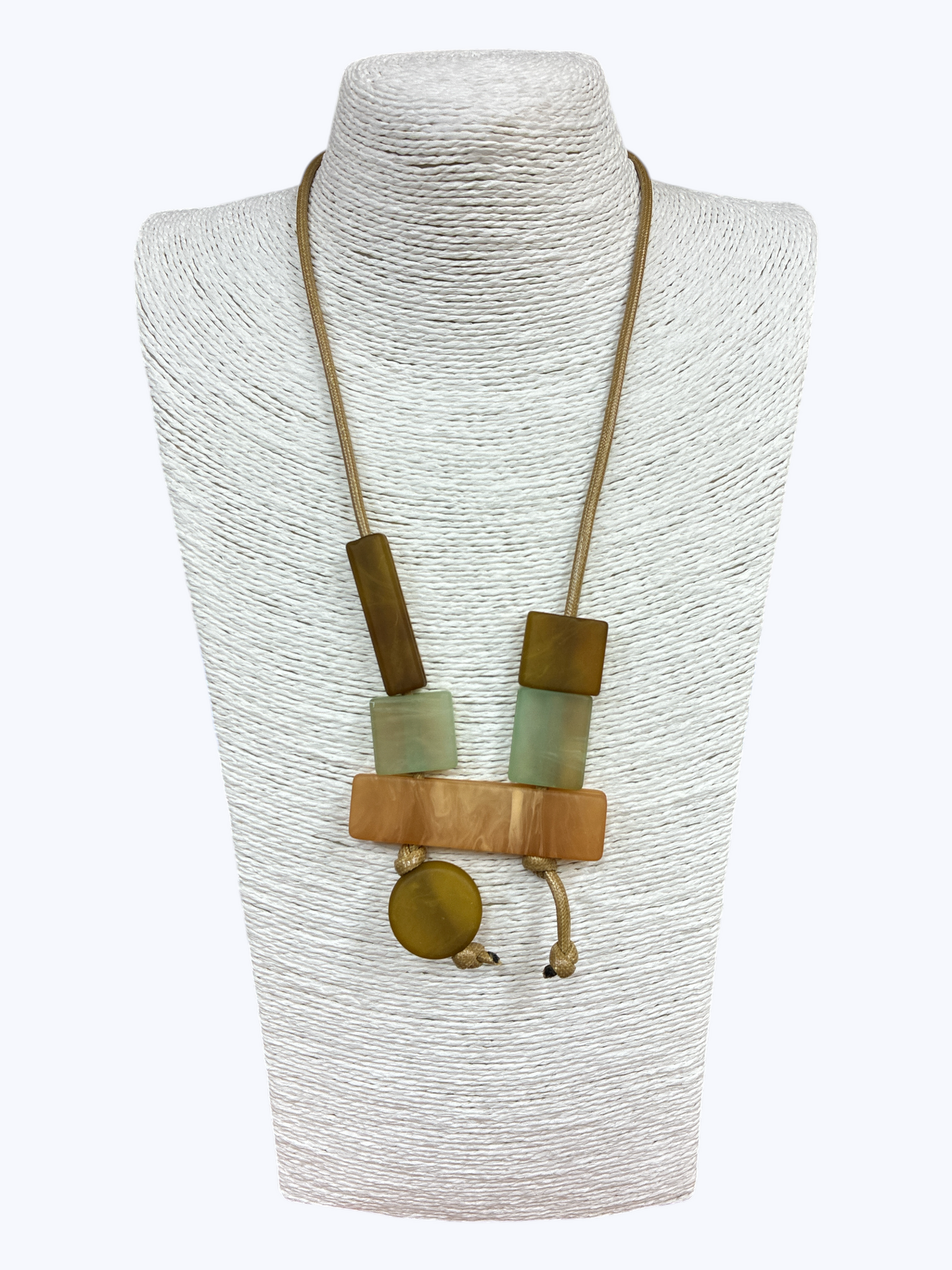 Long pendant necklace with geometric resin and wood-like blocks in a modern abstract arrangement on a cord, displayed on a mannequin bust