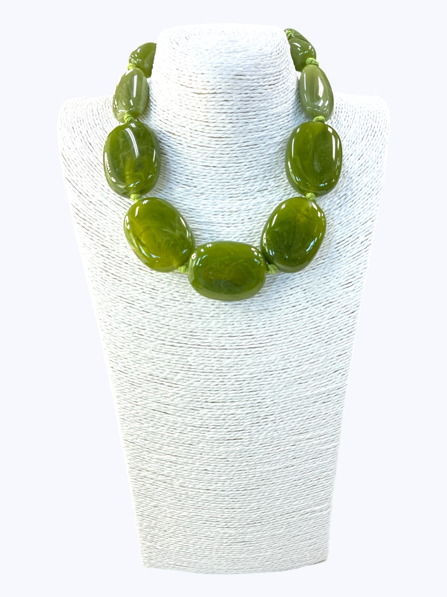 Green necklace on a white textured stand