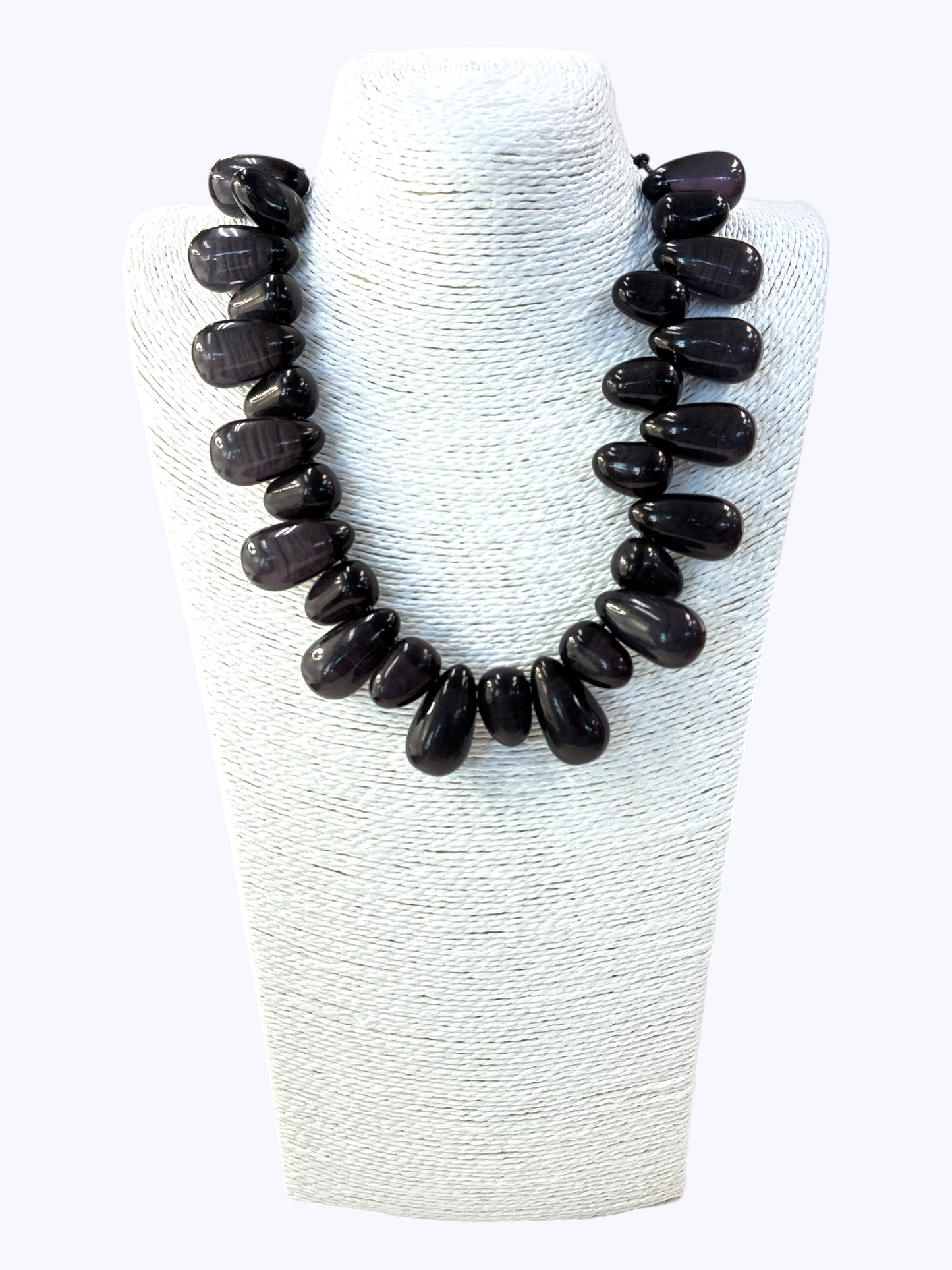 Black beaded necklace on a white textured stand