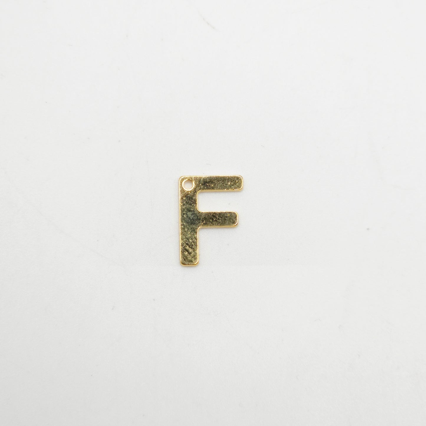 Gold letter 'F' charm on a white background