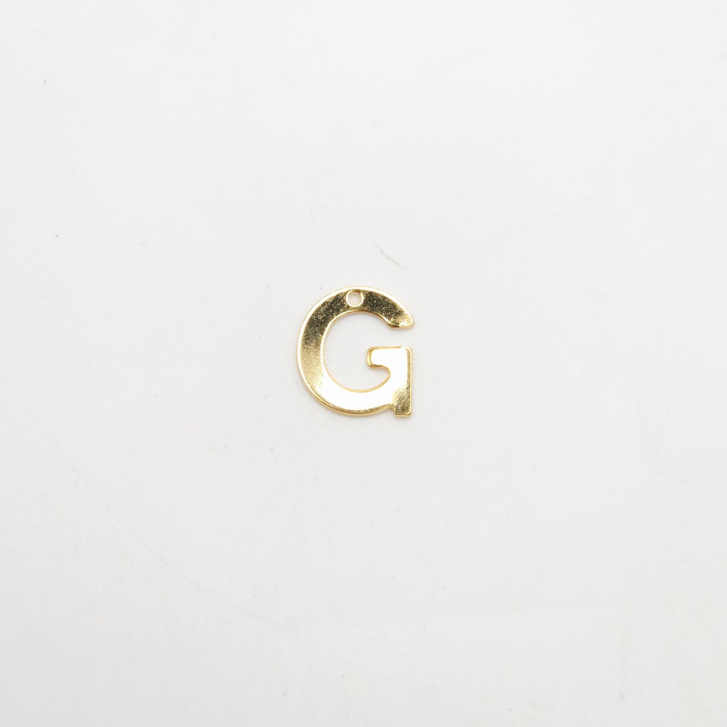 Gold letter 'G' charm on a white background