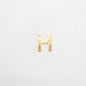 Gold letter 'H' charm on a white background