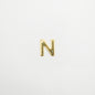 Gold letter 'N' charm on a light gray background