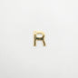 Gold letter 'R' charm on a white background