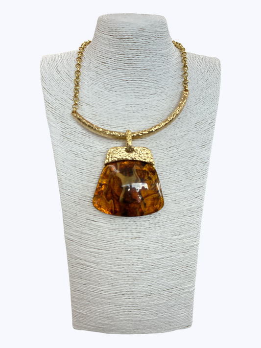 Modern boutique necklace featuring textured metallic collar chain with oversized faux amber resin geometric pendant.