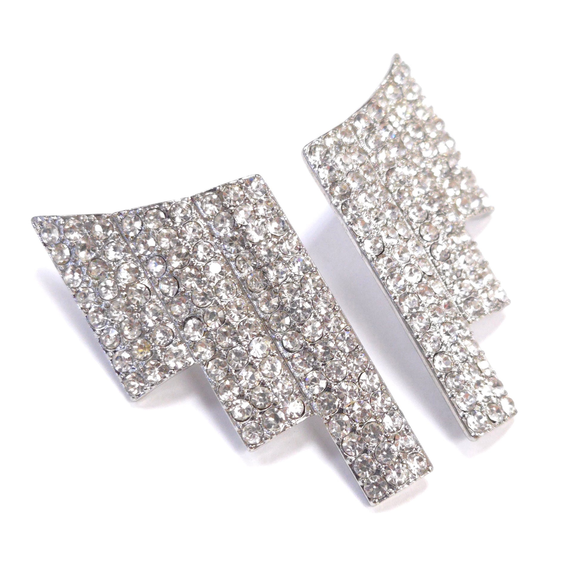 Pair of silver arrow-shaped earrings with clear gemstones on a white background