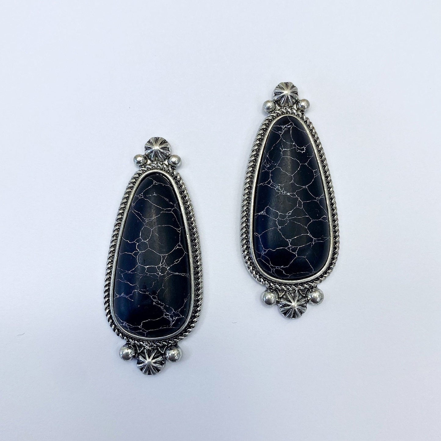 A pair of vintage style drop post earrings with a black stone design and metallic accents.