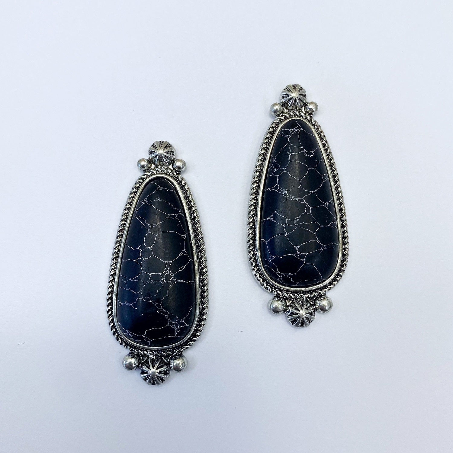 A pair of vintage style drop post earrings with a black stone design and metallic accents.