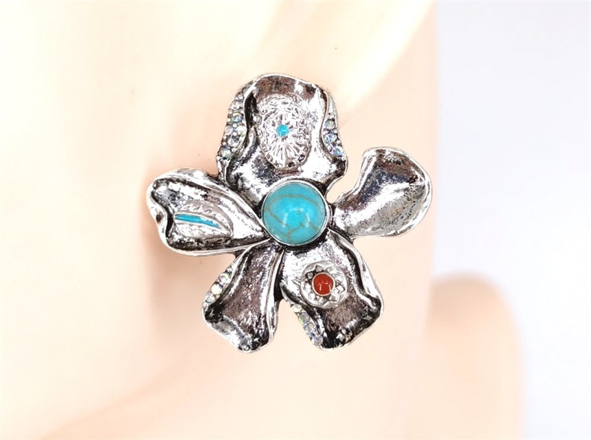 Silver flower-shaped ring with gemstones on a neutral background