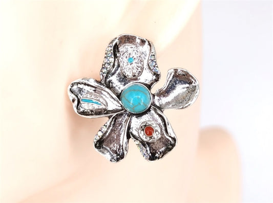 Silver flower-shaped ring with gemstones on a neutral background