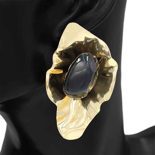 Gold brooch with a central blue stone on a black background