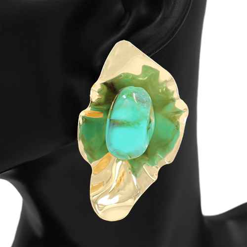 Gold brooch with a green gemstone on a black background