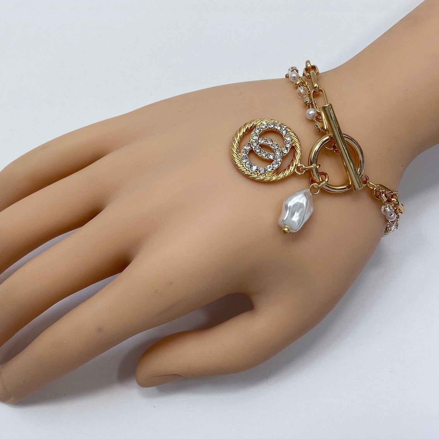 Freshwater Pearl Charm and Cable Gold circle with clear Rhinestone Double 'O' inside both attached to Gold link and a pearl link toggle closure bracelet