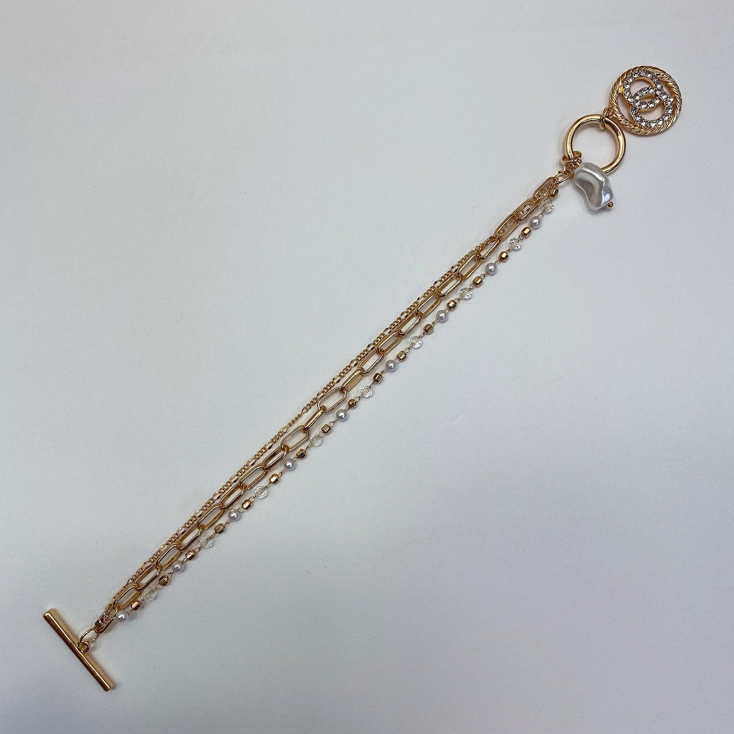 3 individual bracelets linked together with a toggle closure one is a dainty pearl link, a medium sized elongated link and a mini long short link