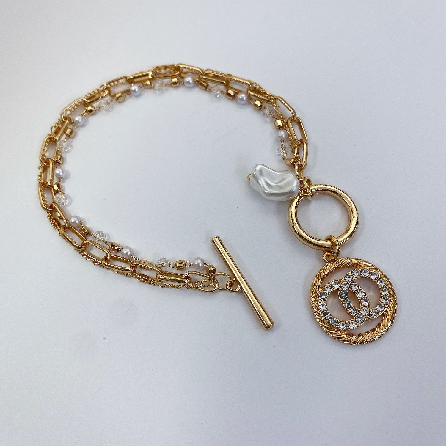3 individual bracelets linked together with a toggle closure one is a dainty pearl link, a medium sized elongated link and a mini long short link