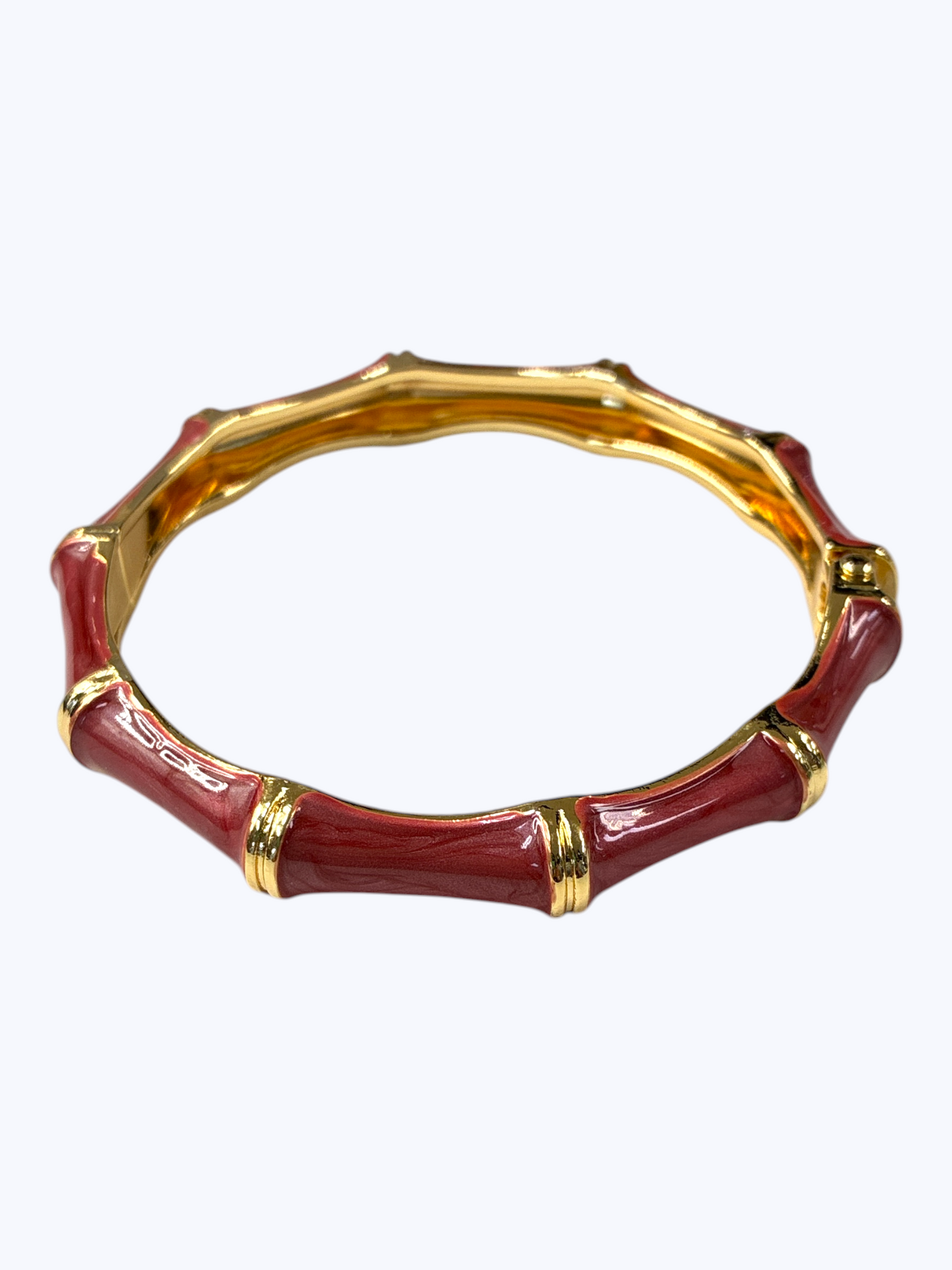 Red bamboo-style bracelet with gold accents on a white background