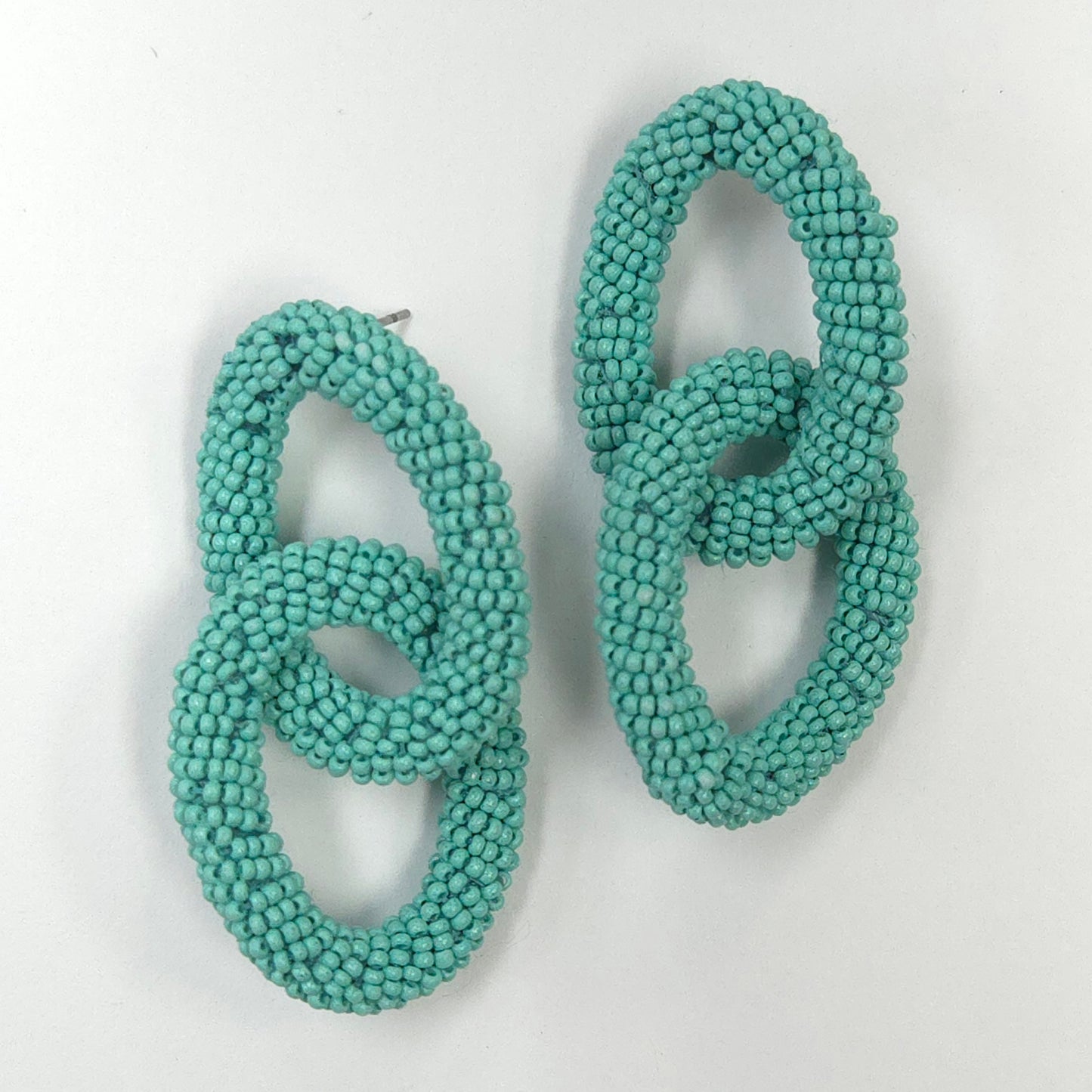 Pair of turquoise beaded earrings on a light gray background