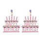 Pink &#39;Happy Birthday&#39; cake-shaped earrings with rhinestone details on a white background