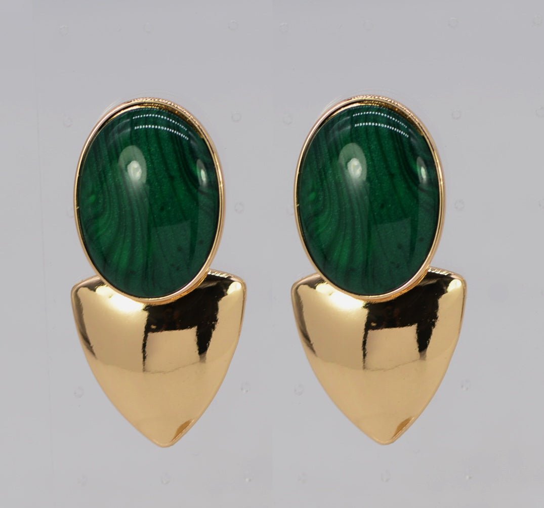 Gold earrings with green gemstones on a gray background