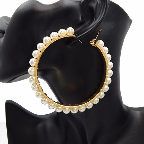 Oversized hoop earrings with pearl trim detailing along the outer edge on a mannequin ear display